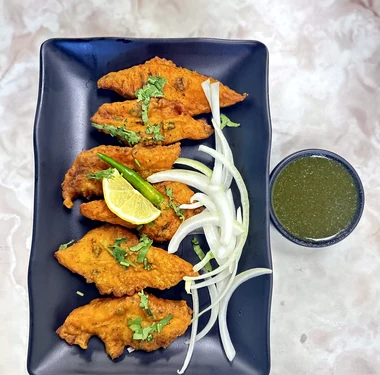 Orange-golden appetizer pieces with onions, lime and green chutney at Lutf Indo-Pak Cuisine