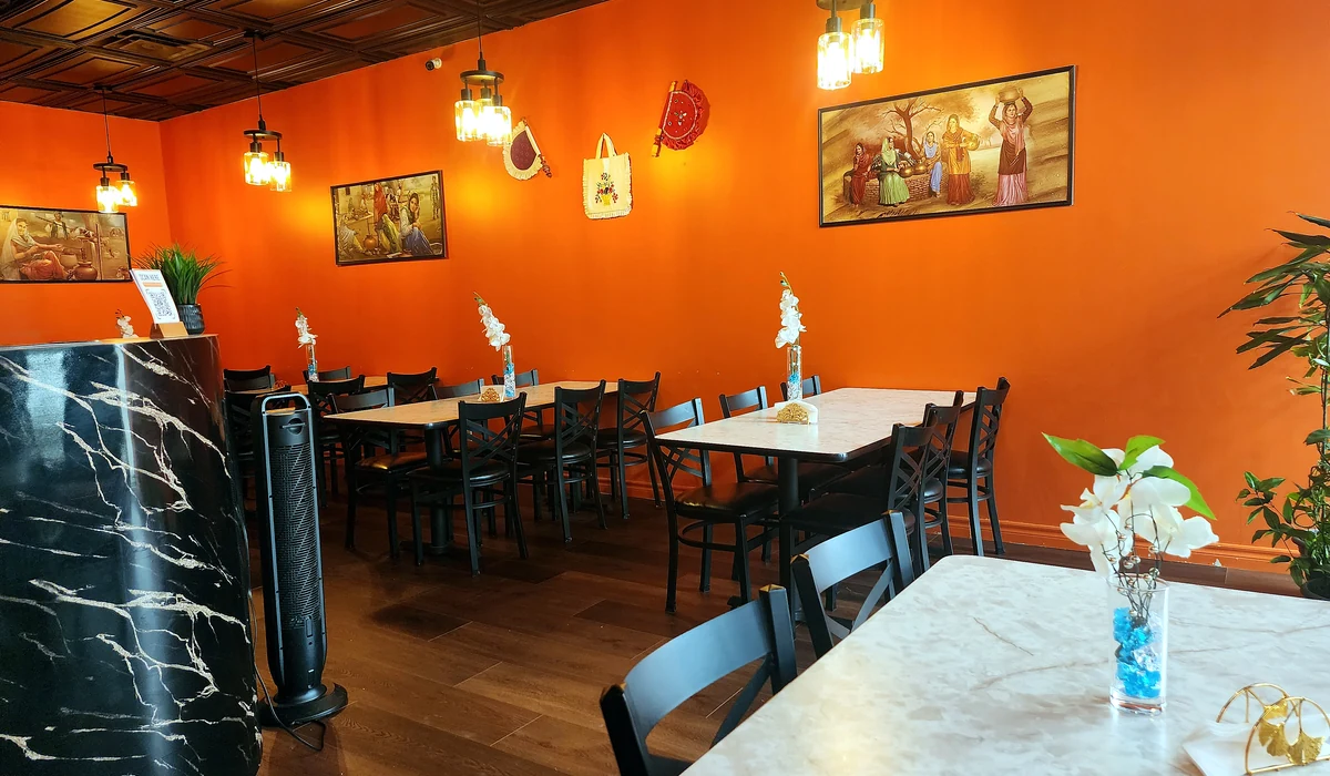 Warm orange dining room with tables and pendant lights at Lutf Indo-Pak Cuisine